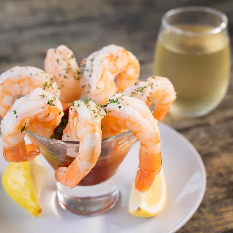 Shrimp Cocktail, served on the table with glass of white wine.