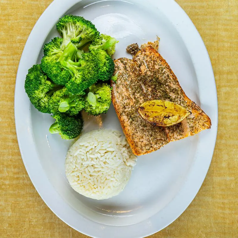 Grilled salmon fillet sauteed in lemon, white wine, honey, and dill, served with broccoli and rice.