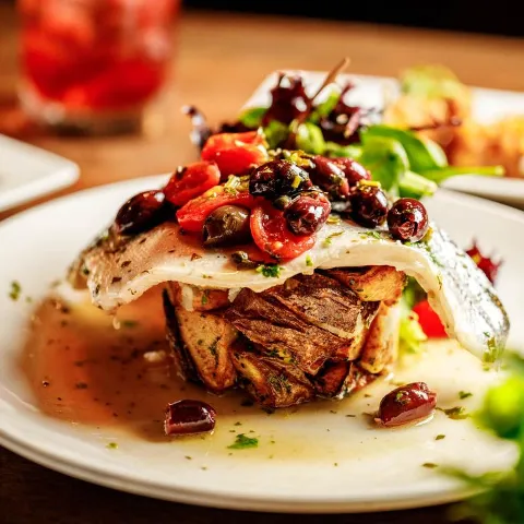 Branzino in white wine reduction with kalamata olives, capers, and cherry tomatoes.