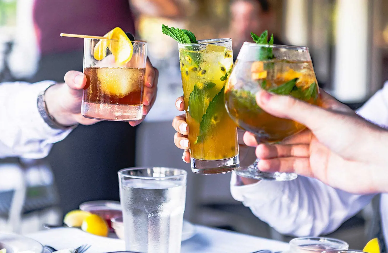 Hands toasting drinks over a dinner table