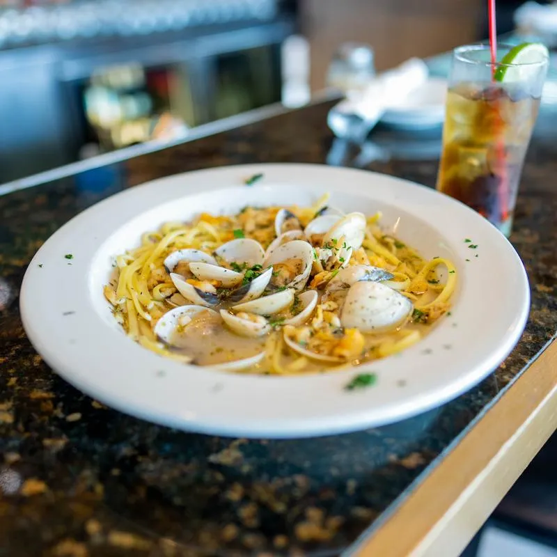 Sea food pasta dish served with a drink.