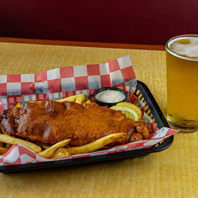 Beer battered fish, fries, and a glass of beer.
