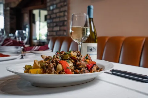 Sausage and peppers with potatoes, served with white wine in the dining room